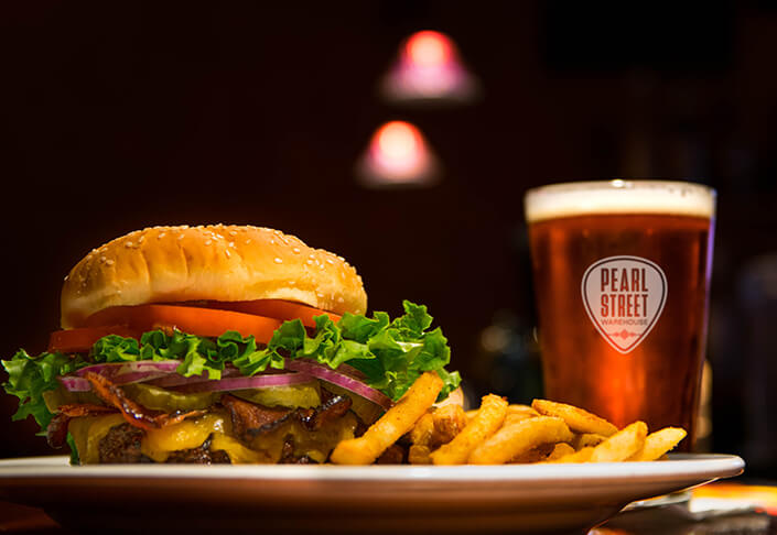 Burger, fries and beer in a glass featuring the Pearl Street logo.