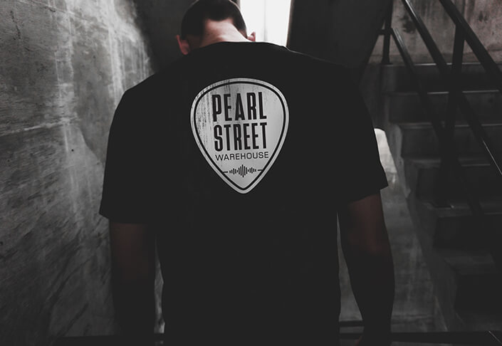 Man wearing a black t-shirt with a Pearl Street logo on the back.