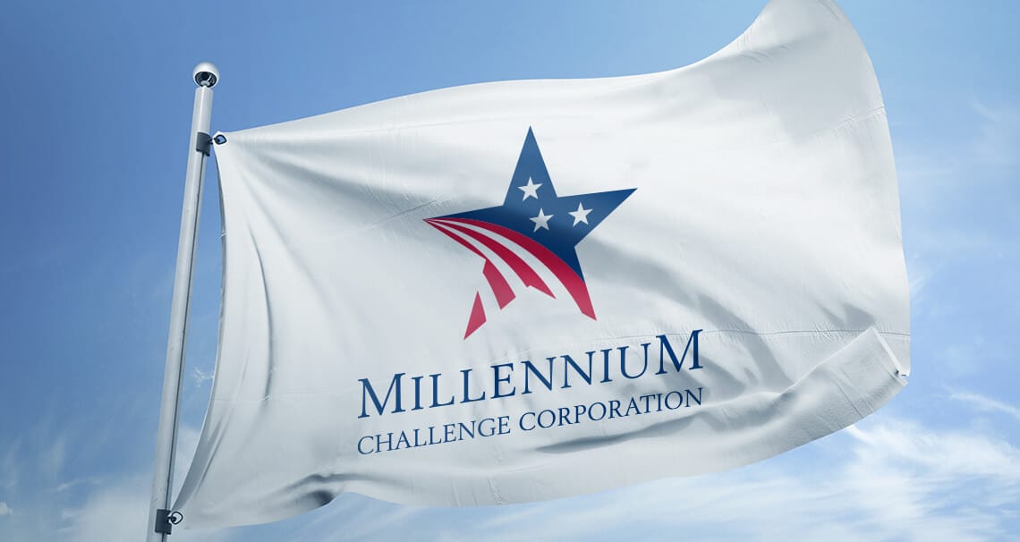 Millennium Challenge Corporation branded flag displayed at a field location